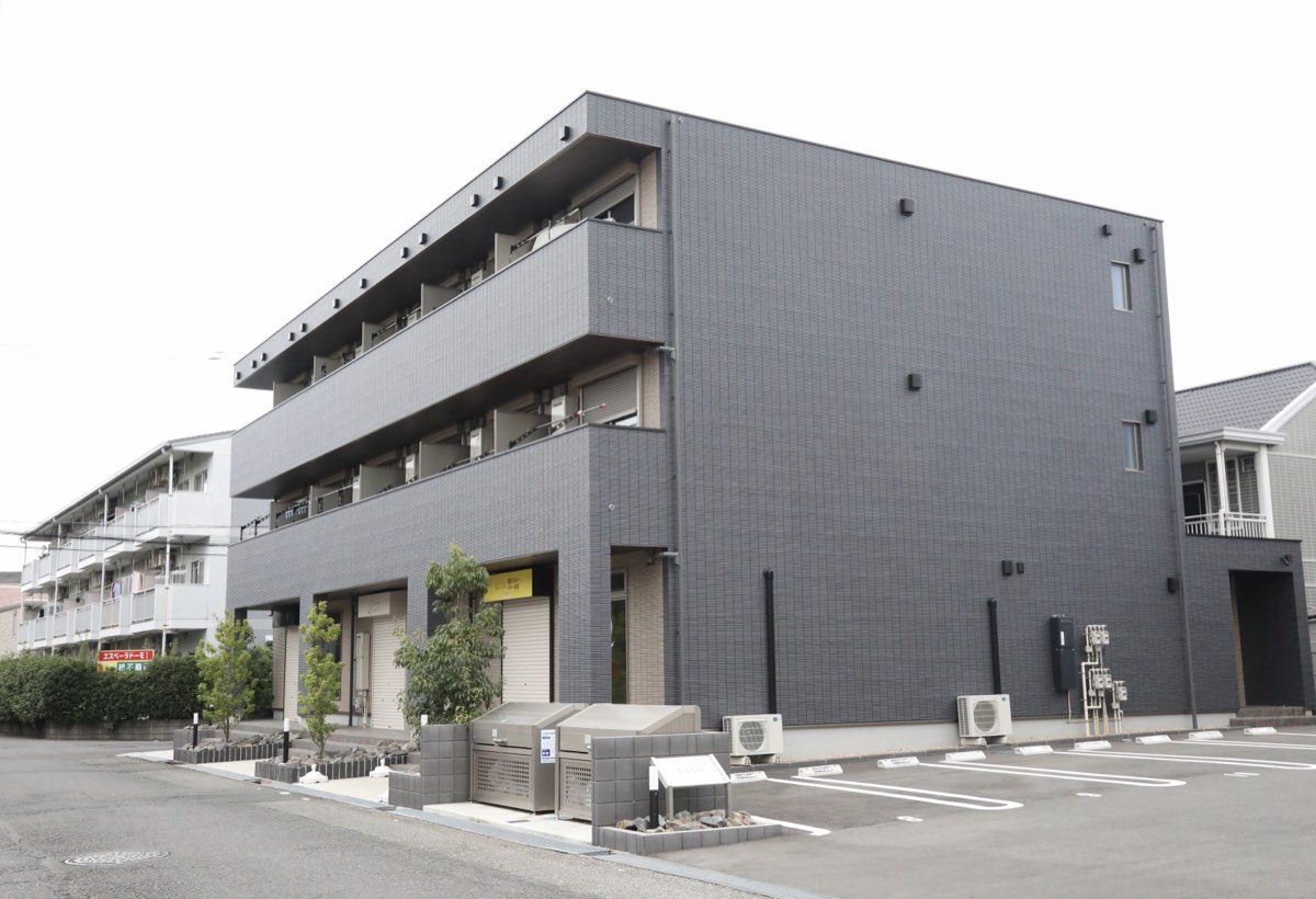 サロンが入る、黒いタイル貼りの3階建ての建物。前面に駐車場がある